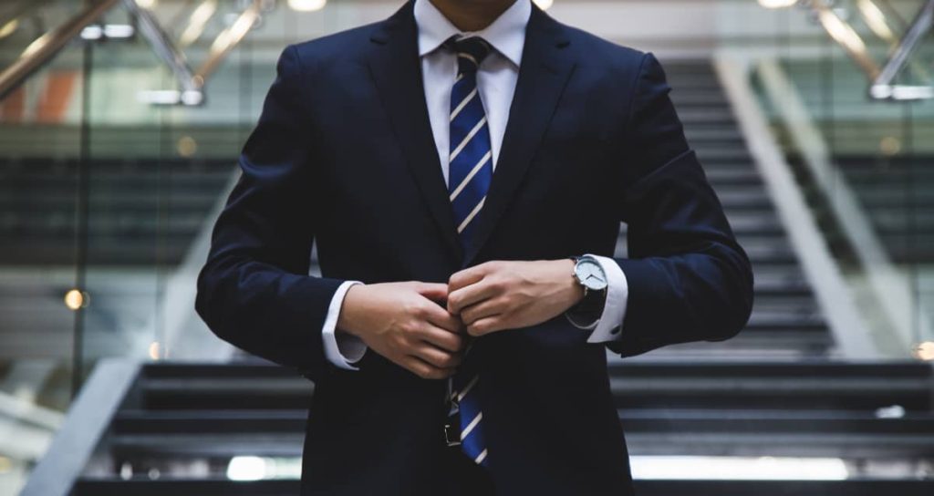 Close-up of a well-dressed man adjusting his tie, representing the outward appearance of success despite underlying alcohol abuse in Austin Texas