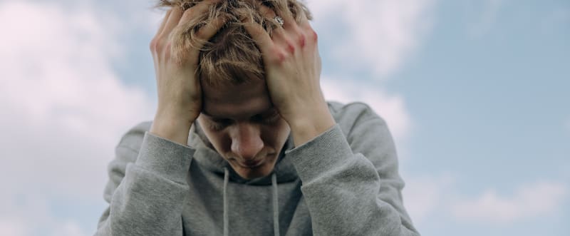 A man sitting with his head in his hands, appearing distraught and overwhelmed, potentially highlighting the emotional toll of Klonopin addiction and the importance of seeking help and support for recovery.