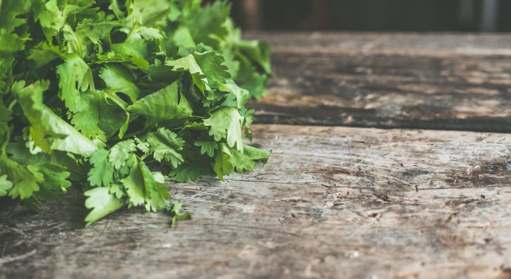 Fresh green leafy vegetables spread out on a cutting board, symbolizing the importance of nutrition in substance abuse recovery in Austin, Texas