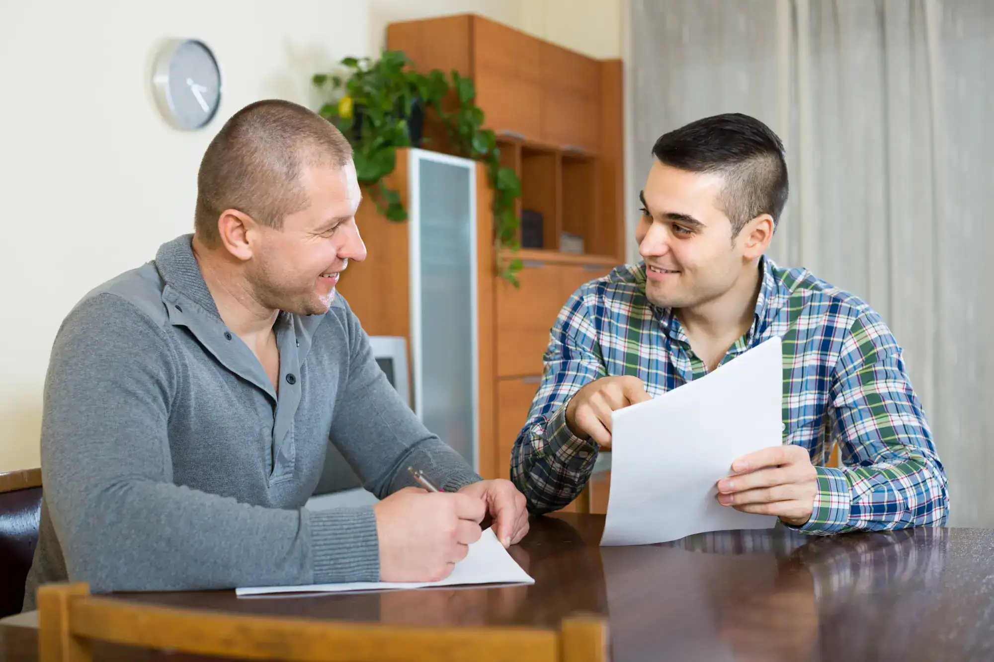 Two men reviewing insurance paperwork together at a table during an Aetna benefits check