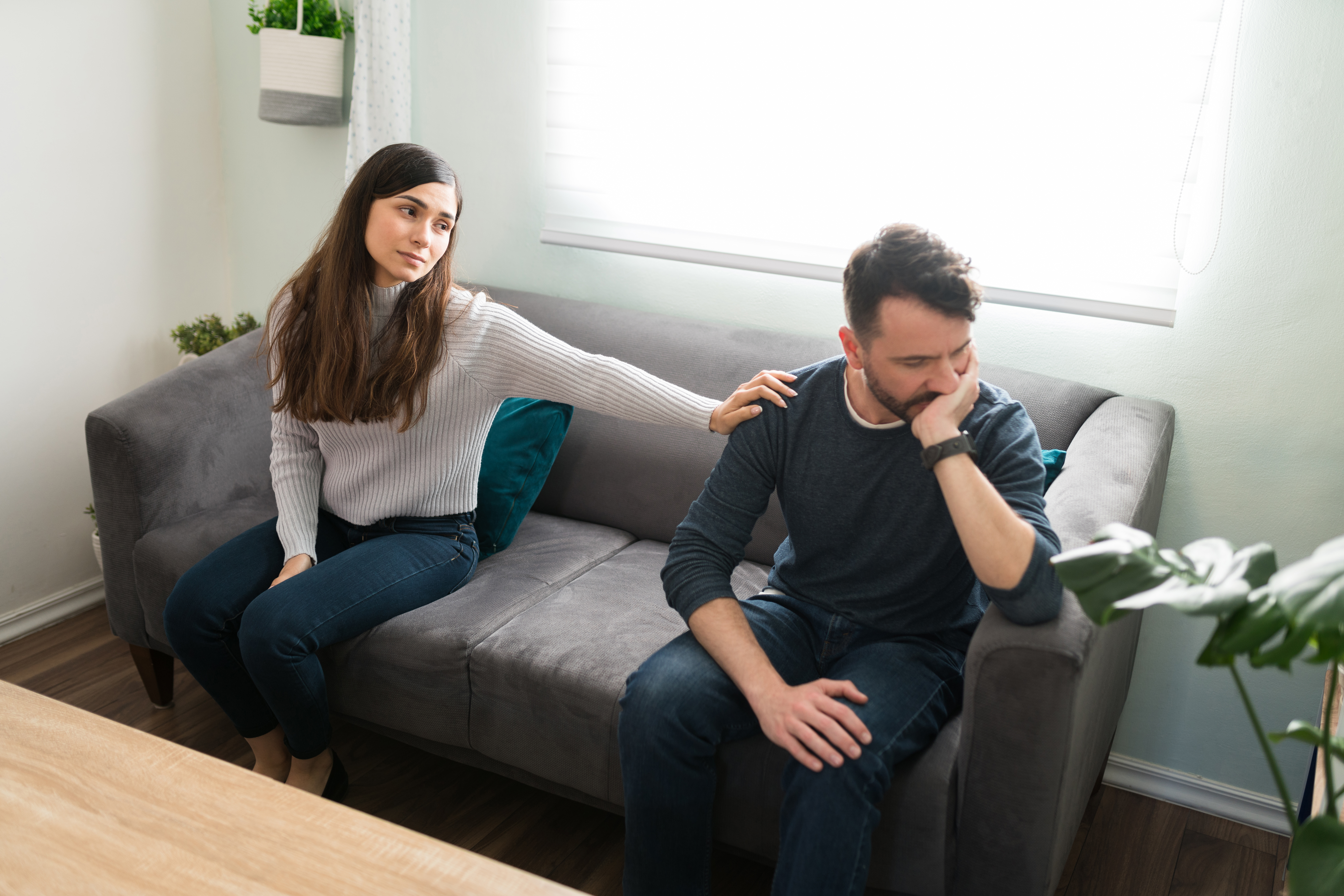 A woman placing her hand on her boyfriend's shoulder wondering how to help an alcoholic boyfriend.