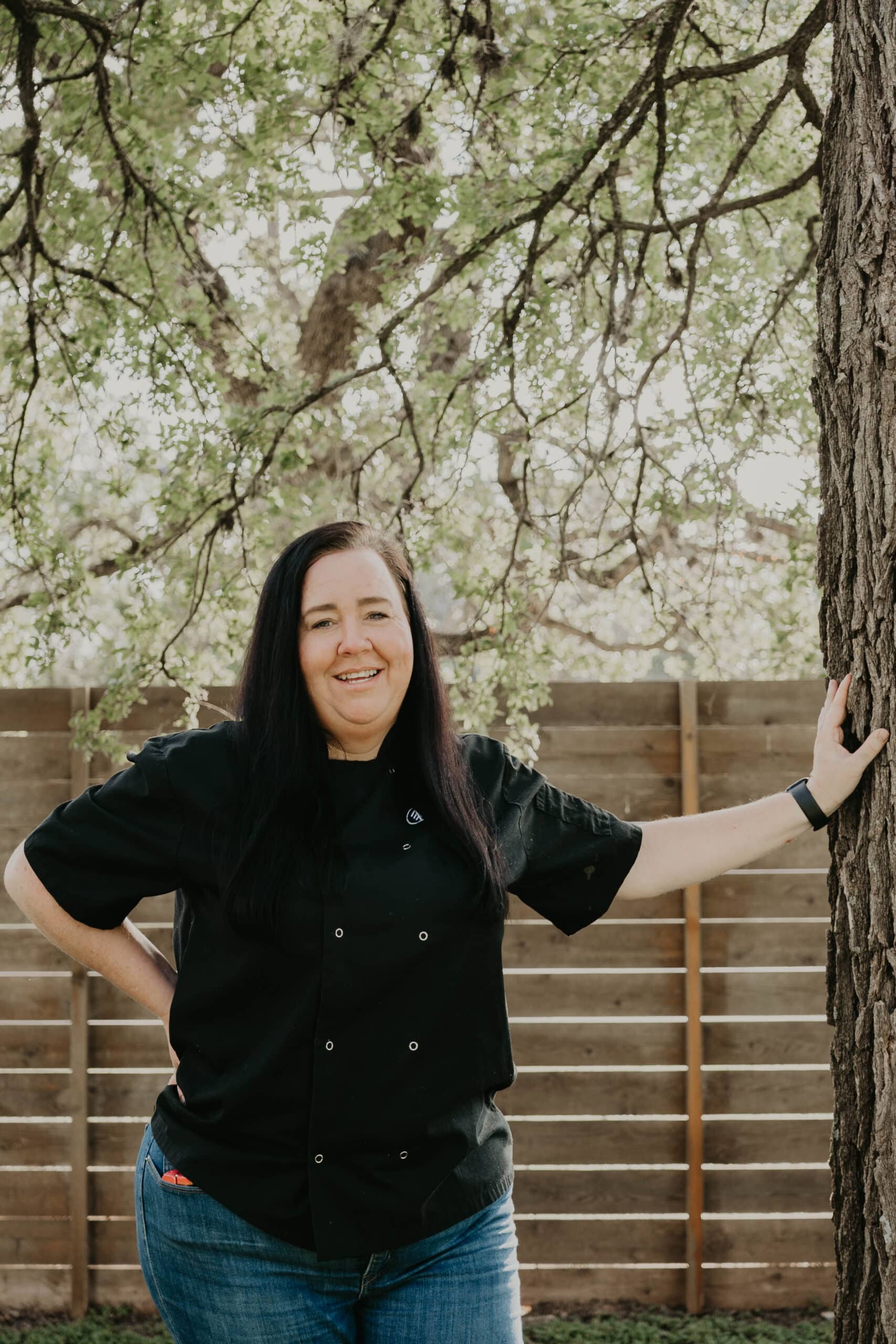 Smiling woman in black chef coat outdoors at Heartwood Recovery.
