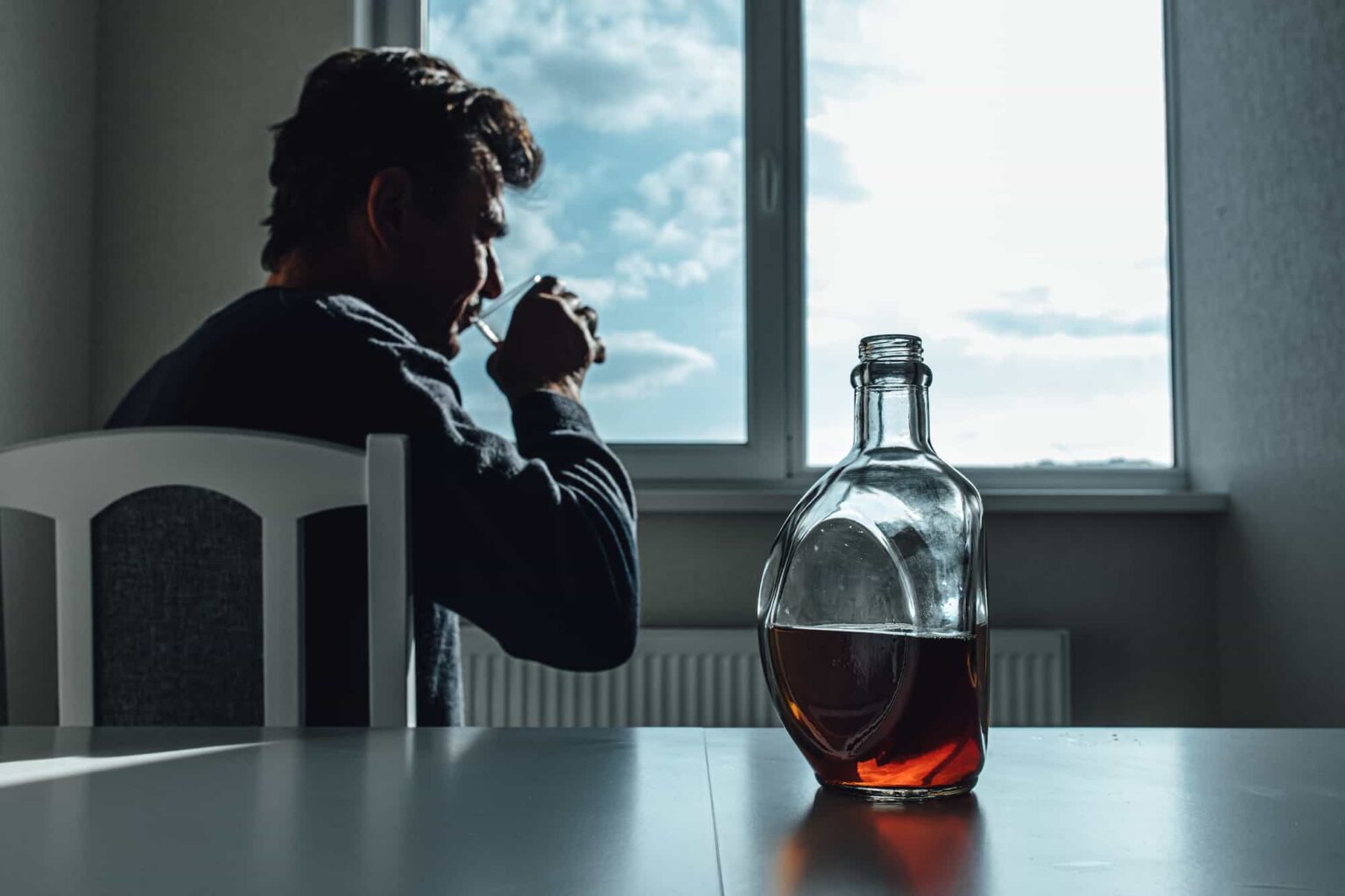 person drinks while sitting by the window