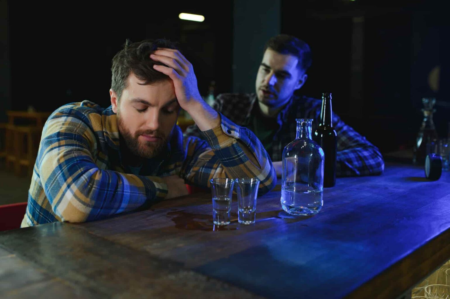 sad man sitting at the bar counter and a family member is trying to speak to him