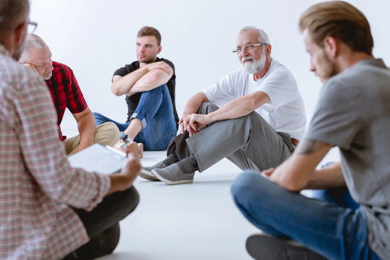 Group of men sitting in a circle during a group therapy session